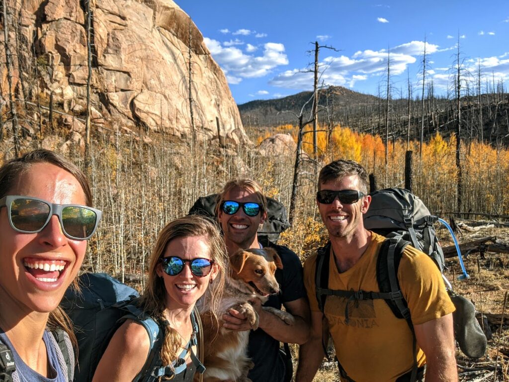 four people and a dog enjoying a good lifestyle with rocks and trees in the background