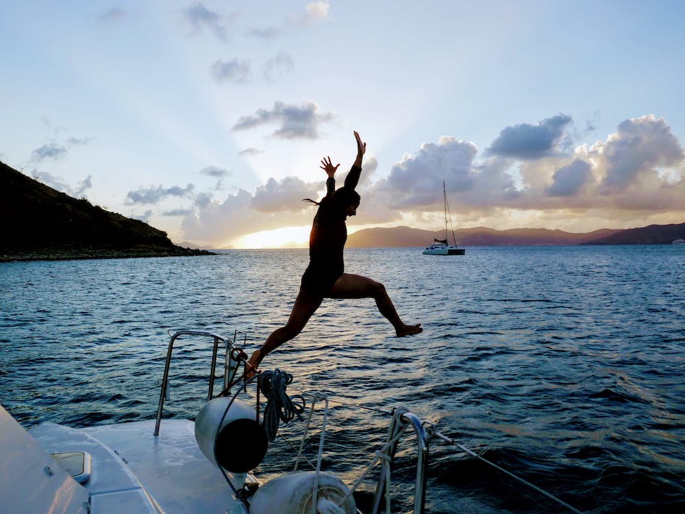 woman jumping off a boat at sunset